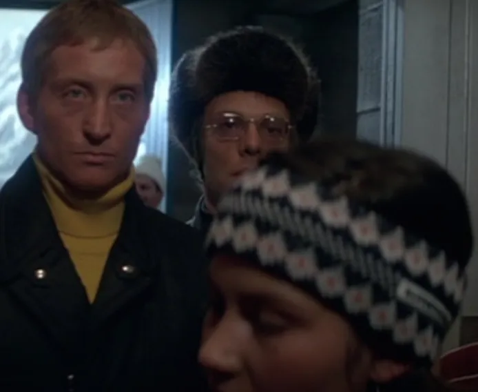 Three suspicious men in winter gear, one sporting a striking gold turtleneck, in For Your Eyes Only